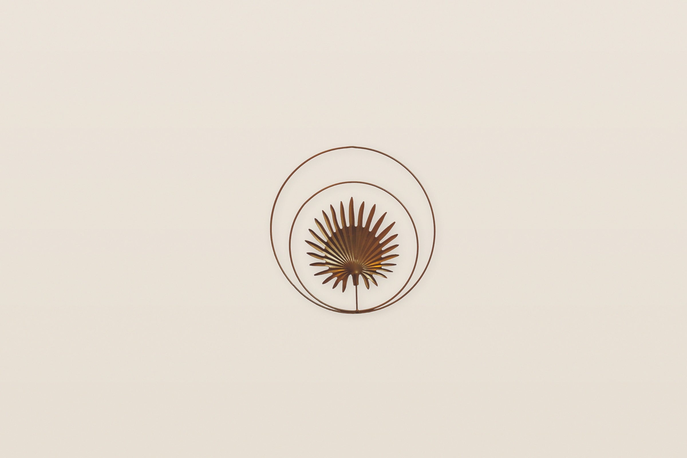 Goldenes Palmblatt-Wandsymbol im Doppelkreis auf heller Putzwand – QuantumSeele Raumgestaltung